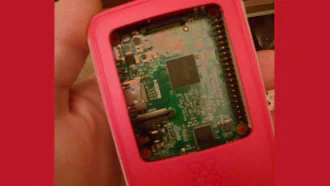 Official Raspberry Pi case showing circuit board, held in a human hand