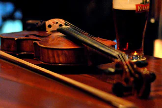 A violin lying down beside a beer
