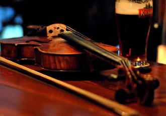 A violin lying down beside a beer